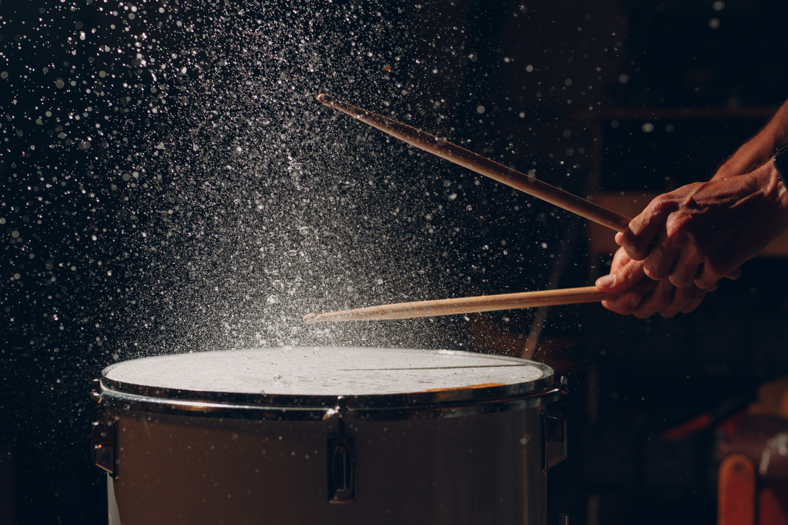 Drum sticks drumming beat rhythm on drum surface with splash water drops